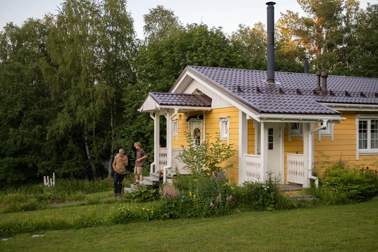 Two people standing outside of a yellow house.