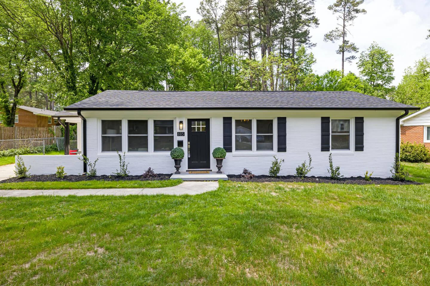 A white house with black shutters and a green lawn.