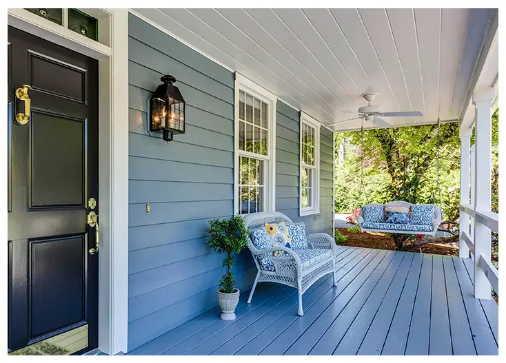 A blue house with a white bench and couch